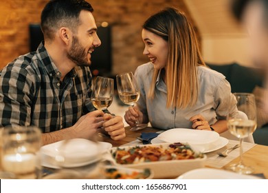 Young happy couple toasting with wine while eating dinner in dining room. 