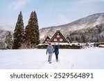 Young happy couple traveler enjoying at Shirakawago with snow in winter, Japan