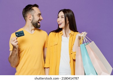 Young Happy Couple Two Friends Family Man Woman Together In Yellow Casual Clothes Hold Package Bags With Purchases After Shopping Credit Bank Card Isolated On Plain Violet Background Studio Portrait