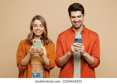 Young happy couple two friends family man woman wear casual clothes hold in hand use mobile cell phone together surfing internet isolated on pastel plain light beige color background studio portrait - Powered by Shutterstock