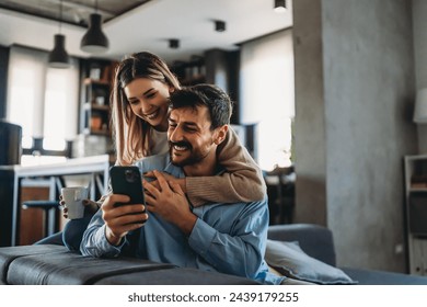 Young happy couple using phone to share social media news at home, doing shopping online. - Powered by Shutterstock