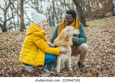 Young happy couple walking with dog near the lake in autumn. Couple Walking Dog Through Winter Woodland With Linked Arms. Couple with pet dog relaxing while hiking at forest  - Powered by Shutterstock