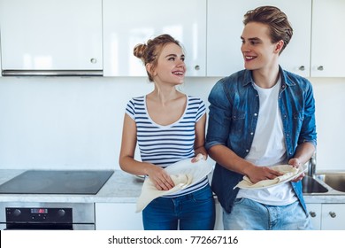 Young Happy Couple Is Washing Dishes While Doing Cleaning At Home.