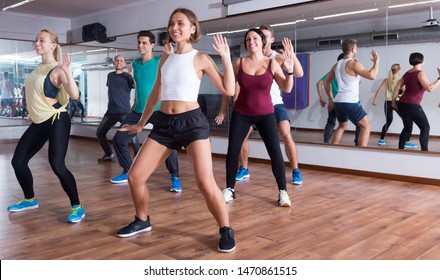 Young happy dansers studying zumba elements in dancing class - Powered by Shutterstock