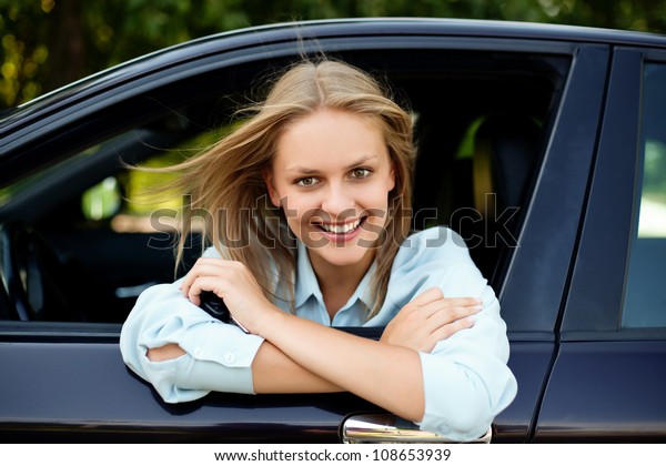 Young happy
driver sitting in car with key in
hand