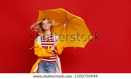 young happy emotional cheerful girl laughing and jumping with yellow umbrella   on colored red background