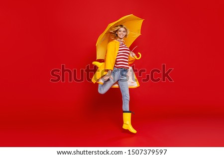 young happy emotional cheerful girl laughing  with yellow umbrella   on colored red background
