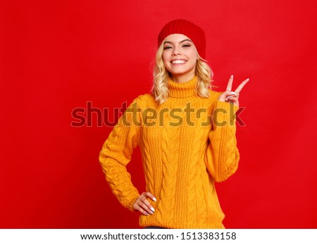 young happy emotional cheerful girl laughing  with knitted autumn cap   on colored red background
