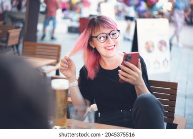 Young Happy European Woman 30 Years Old Hipster With Pink Hair With A Smartphone In Her Hands In A Street Cafe