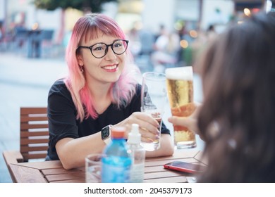 Young Happy European Woman 30 Years Old Hipster With Pink Hair Drinking Beer With Girlfriend In Street Cafe In City