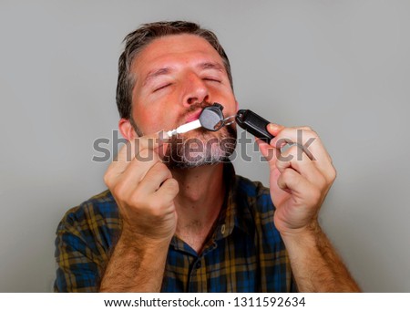 young happy and excited 30s or 40s attractive man kissing car key celebrating buying new automobile or motorbike isolated on grey background