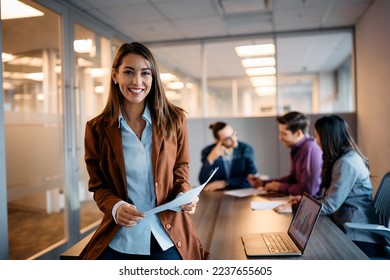 Young happy executive manager holding business meeting with her coworkers in the office and looking at camera.  - Powered by Shutterstock