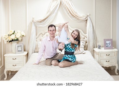 Young Happy Family With A Baby Having Fun On Bed At Home