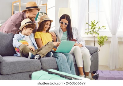 Young happy family booking tickets online via laptop in internet sitting on sofa in living room at home together. Parents with kids waiting for summer vacation trip. Travel concept. - Powered by Shutterstock