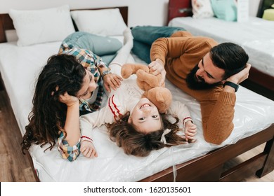 Young Happy Family Buying New Bed And Mattress In Big Furniture Store