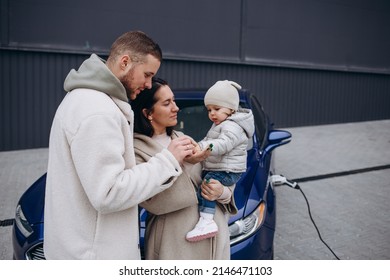 A Young, Happy Family Charges An Electric Car