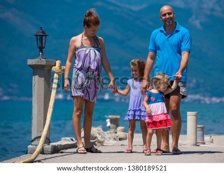 young happy family with cute little daughters holding their hands while walking by the sea during Summer vacation  Healthy family holiday concept