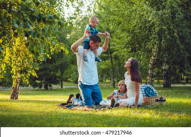 Young Happy Family Of Four On Picnic In The Park