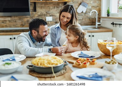 Young Happy Family Having Fun During Lunch Time At Dining Table. 