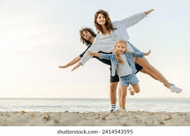 Young happy family having fun while doing yoga excercises on sunny beach. Caucasian parents with daughter keeping balance meditating outdoors - Powered by Shutterstock