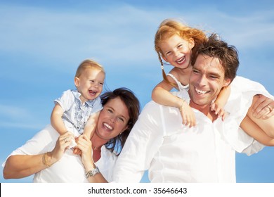 Young Happy Family Having Fun Outdoors, Dressed In White And With Blue Sky In Background