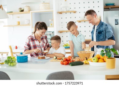 Young Happy Family Making Sandwich At Home. Mom And Dad Preparing Breakfast With Sons.