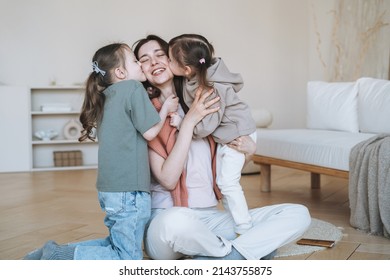 Young Happy Family With Parent Woman Mother With Two Children Girls Kissing Mom In Living Room At Home