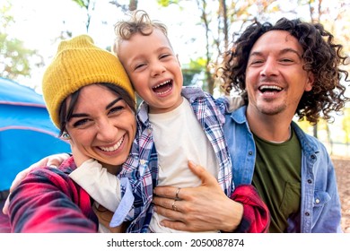 young happy family portrait camping outdoor with tent in autumn nature. mom, dad and little child making a pov selfie into the wild. people having fun together hugging each other smiling. lifestyle - Powered by Shutterstock