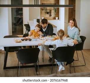 Junge glückliche Familie spricht beim Mittagessen am Esstisch in der Wohnung