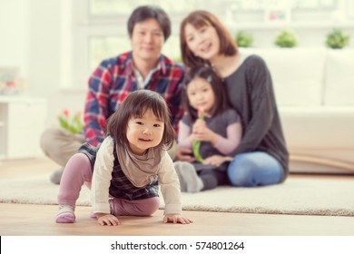 Young happy family with toddler pretty daughters playing together and having fun at home