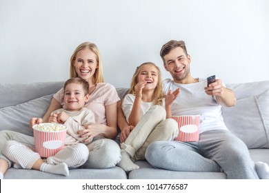 Young Happy Family Watching Movie On Couch At Home