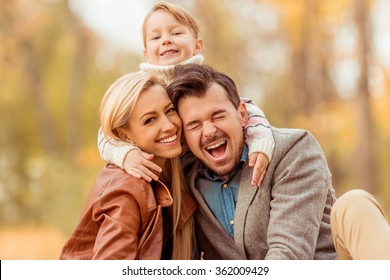 Young Happy Family While Walking In The Autumn Park.