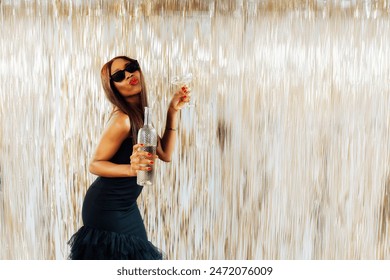 Young happy fashion African girl black woman in cocktail dress and sunglasses holding drink glass and wine bottle dancing at party with glitter background having fun at holiday, birthday celebration. - Powered by Shutterstock