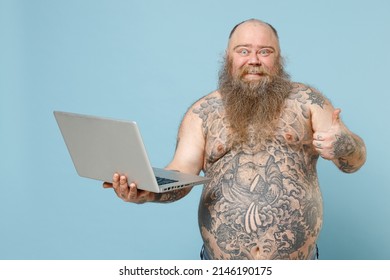 Young Happy Fat Pudge Obese Chubby Overweight Blue-eyed Bearded Man 30s Has Big Belly With Naked Tattooed Torso Holding Laptop Pc Computer Show Thumb Up Gesture Isolated On Pastel Blue Background.