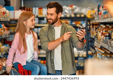 Young happy father with a child buying groceries in a supermarket. A man carries his daughter in a grocery cart, choosing goods and having fun. - Powered by Shutterstock