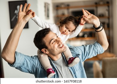 Young happy father having fun with his small daughter while carrying her on his shoulders at home.  - Powered by Shutterstock