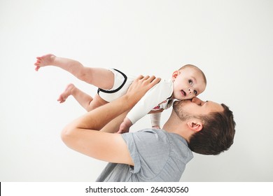 Young Happy Father Holding Baby Son In Hands Over His Head With Isolated Background