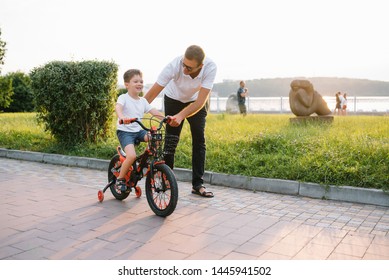 Young and happy father teaches his young son to ride a bike. The child is happy . Father watching son. father's day