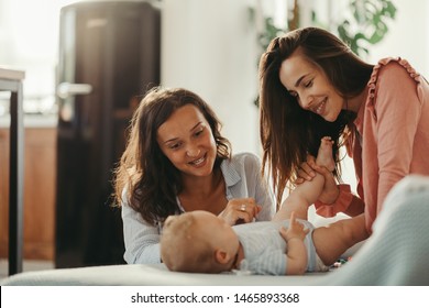 Young Happy Female Couple And Their Baby Enjoying Together At Home. 