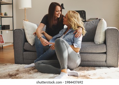 Young Happy Female Gay Couple Sitting On A Sofa And Flirt