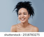 Young happy female with natural beauty and curly hair looking away over a gray background