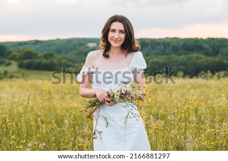 young happy female walking in the field enjoying beautiful sunset. Beautiful countryside. Slow living concept