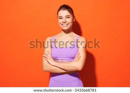 Young happy fitness trainer instructor sporty woman sportsman wear purple top clothes spend time in home gym hold hands crossed folded isolated on plain orange background Workout sport fit abs concept