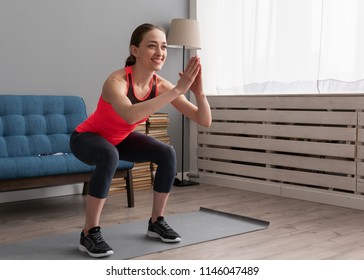 Young Happy Fitness Woman Doing Squat Exercise At Home