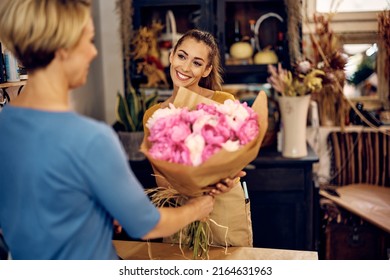 Young Happy Florist Giving Her Customer Bouquet Of Fresh Flowers At Flower Shop.