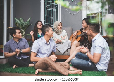 Young happy friends having party, one playing guitar and the other singing together