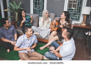Young happy friends having party, one playing guitar and the other singing together - Shutterstock ID 1056518096