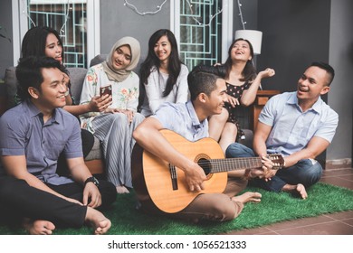 Young happy friends having party, one playing guitar and the other singing together - Shutterstock ID 1056521333