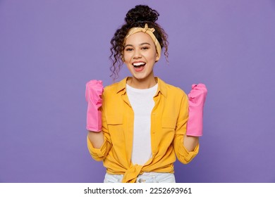 Young happy fun excited woman wear yellow shirt rubber gloves while doing housework tidy up do winner gesture clench fist isolated on plain pastel light purple background studio. Housekeeping concept - Shutterstock ID 2252693961