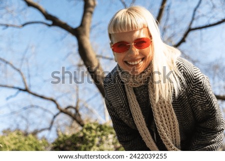 Young happy funny hippie girl showing tongue at camera for fun and making funny faces while wearing cool sunglasses. Attractive female woman enjoying sunny weather expressing her happiness